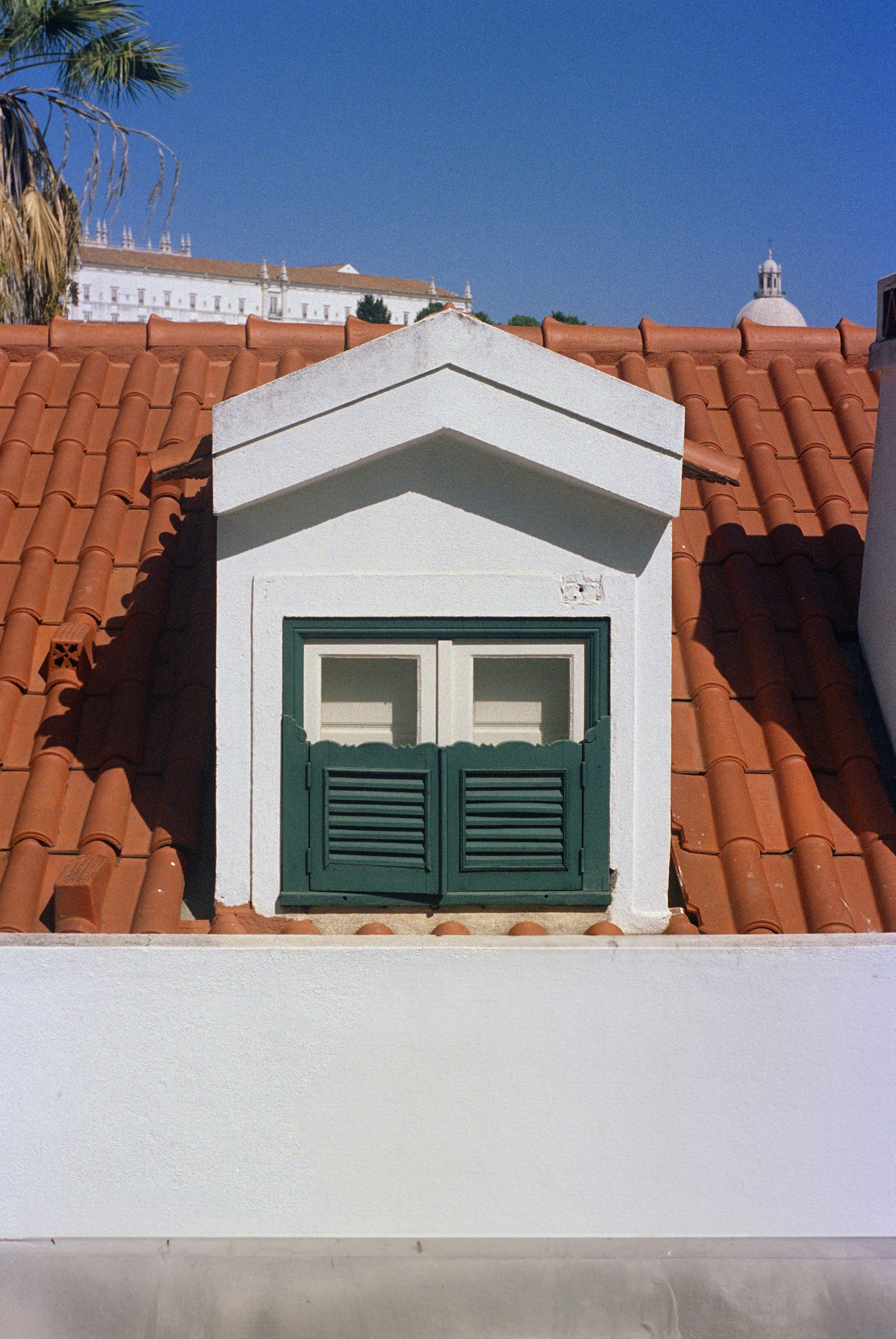 ein weißes Gebäude mit grünen Fensterläden und rotem Dach