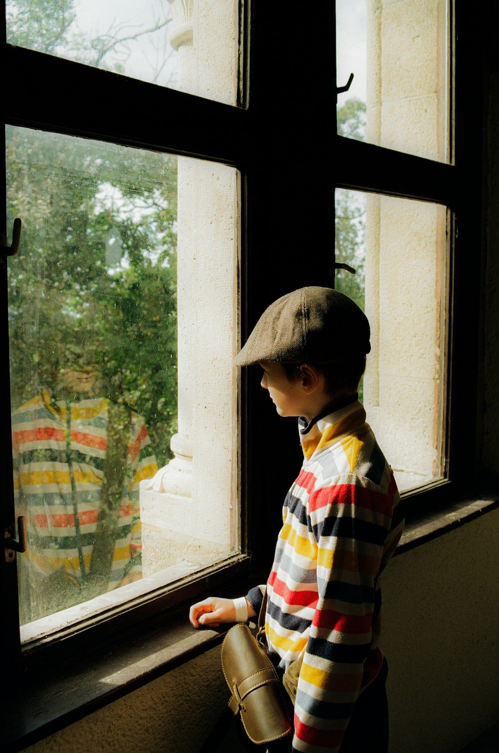 a young boy standing in front of a window