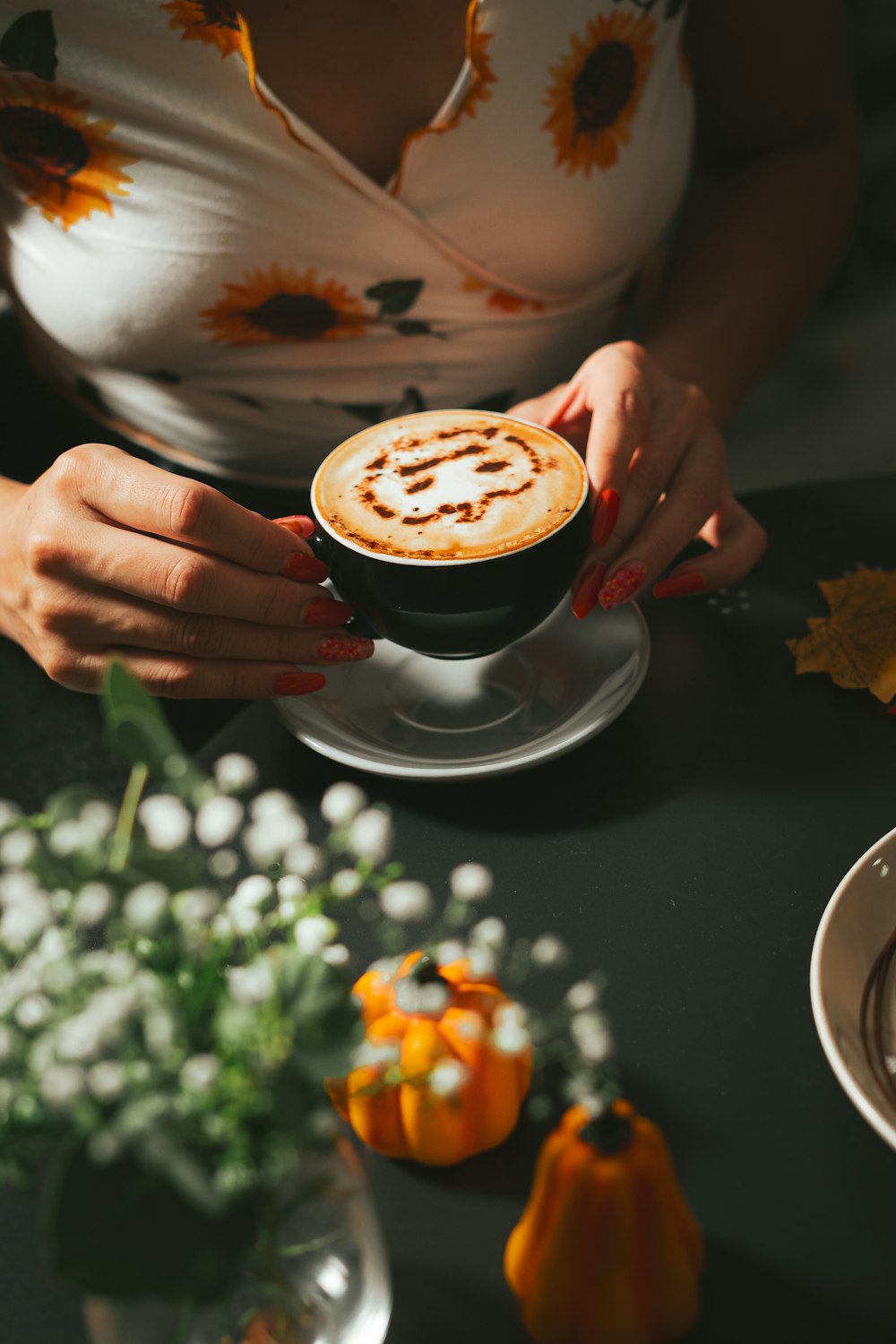 a woman holding a cup of coffee on top of a table