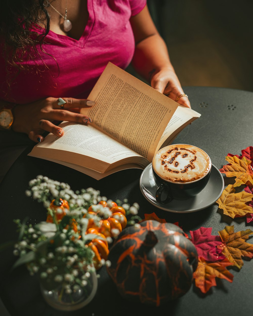 uma pessoa sentada em uma mesa com um livro e uma xícara de café