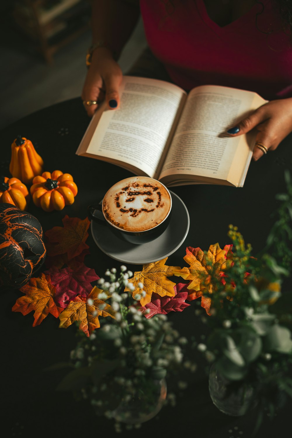 a woman reading a book while holding a cup of coffee