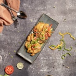 Raw chicken breasts neatly placed on a white plate with red chili peppers.
