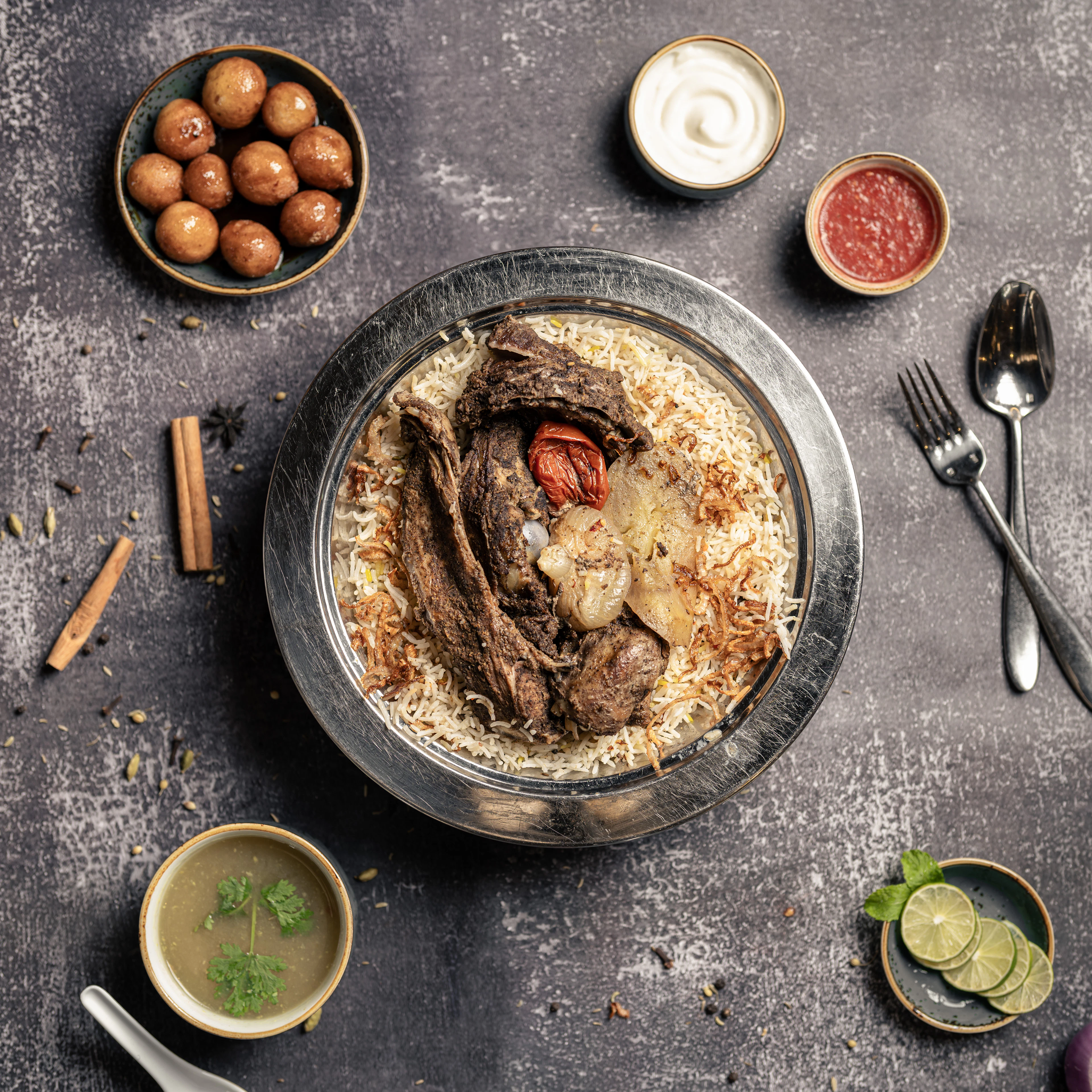 Machboos: spiced rice with slow-cooked meat on a wide platter, ringed by small bowls of spices and sauces
