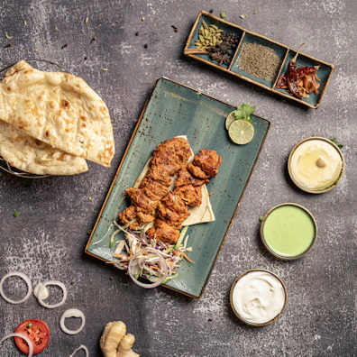 Close-up of sizzling tandoori chicken with charred spices on a rustic platter.