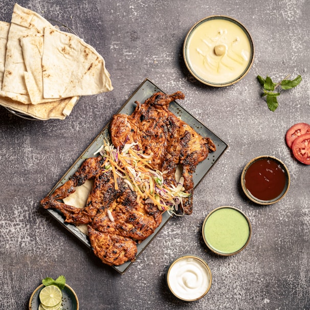 A vibrant platter featuring grilled chicken, fresh sides, and dipping sauces