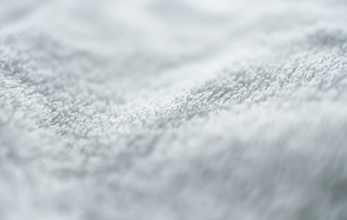 Close-up of a hand feeling the plush texture of a white bath towel.