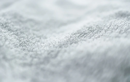 Close-up shot of a luxurious towel fabric under warm light, highlighting its intricate weave and softness.