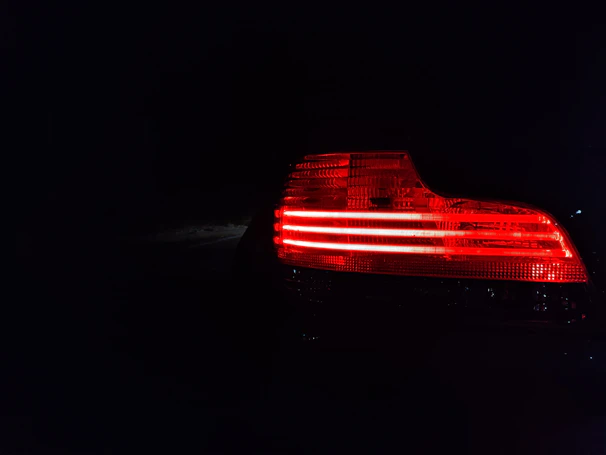 Shiny black and red custom car stoplamp illuminated in a dark setting