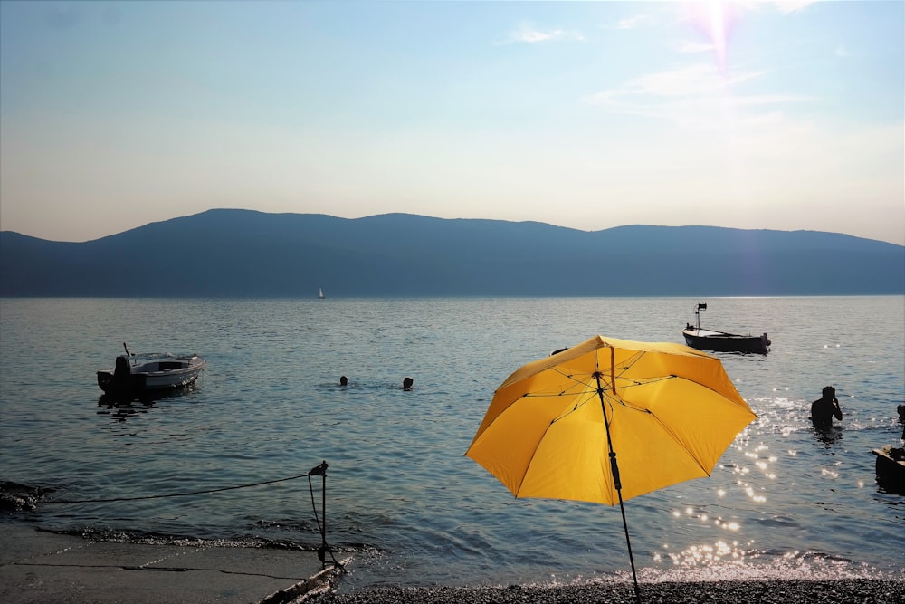 a yellow umbrella sitting on top of a beach next to a body of water