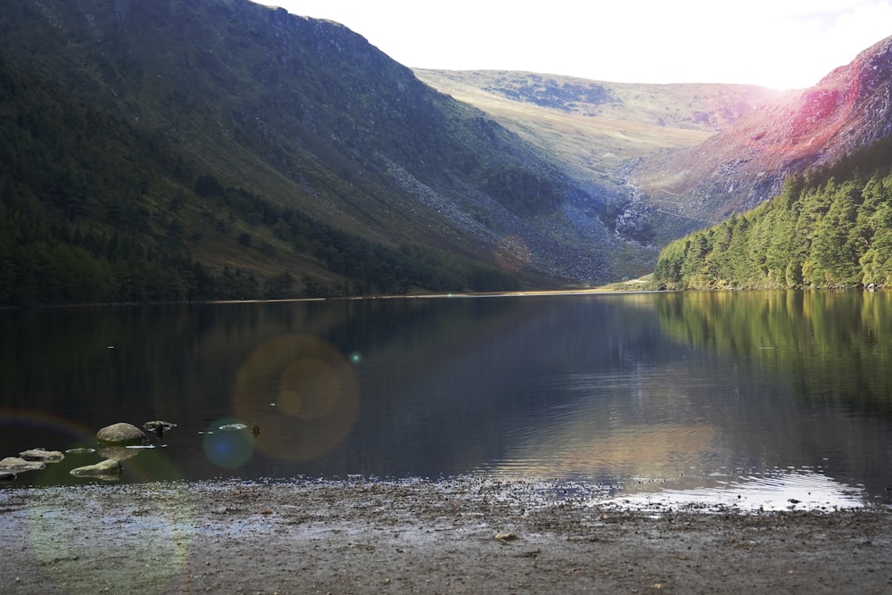 a lake surrounded by mountains with a rainbow in the sky