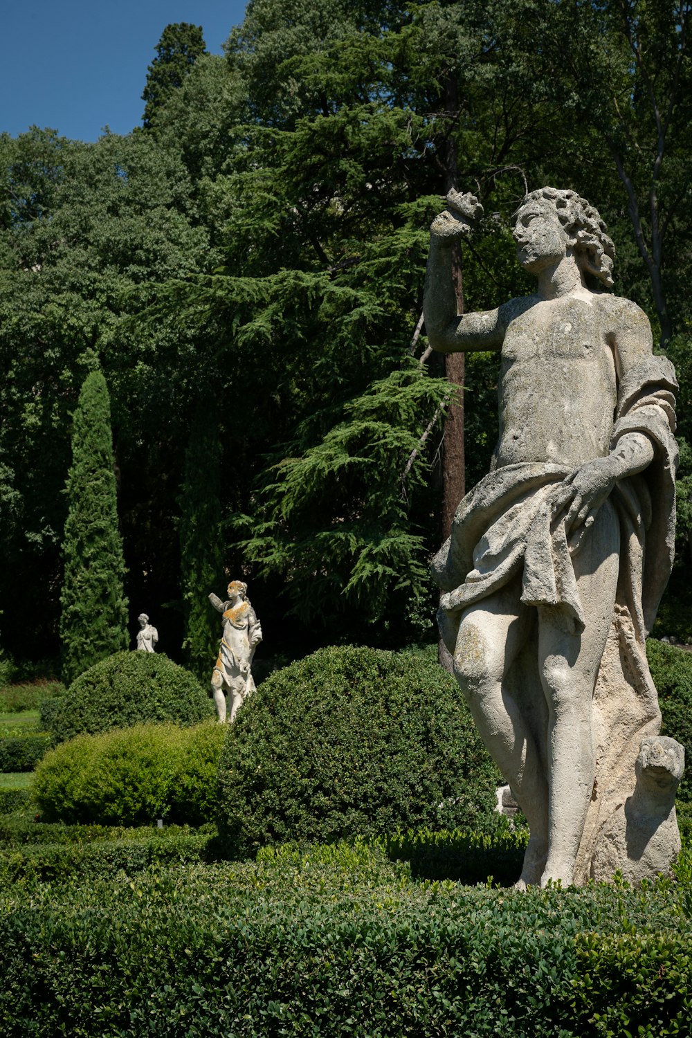 a statue of a man holding a bird in a garden