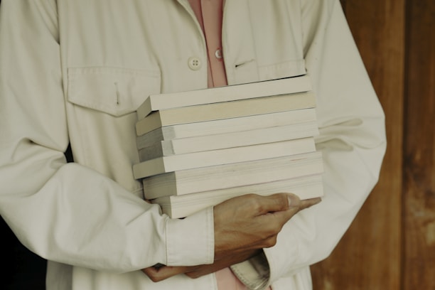 A smiling customer holding a stack of books near a window with soft natural light.