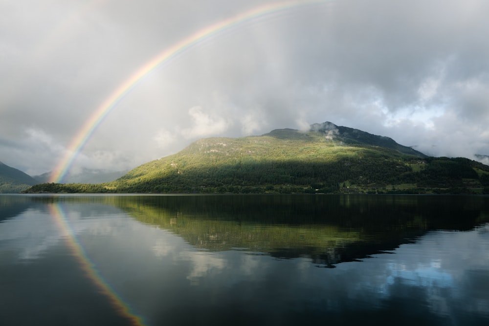 a rainbow over a lake with a mountain in the background
