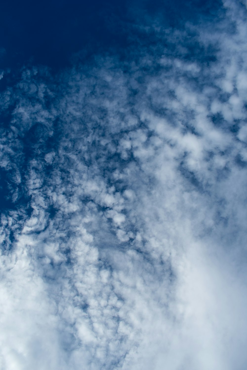 a plane flying through a cloudy blue sky