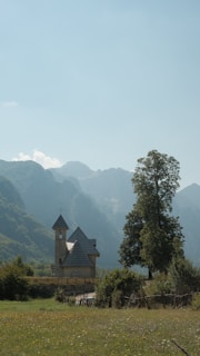 A peaceful stone church nestled among rolling green hills under a soft morning sky.
