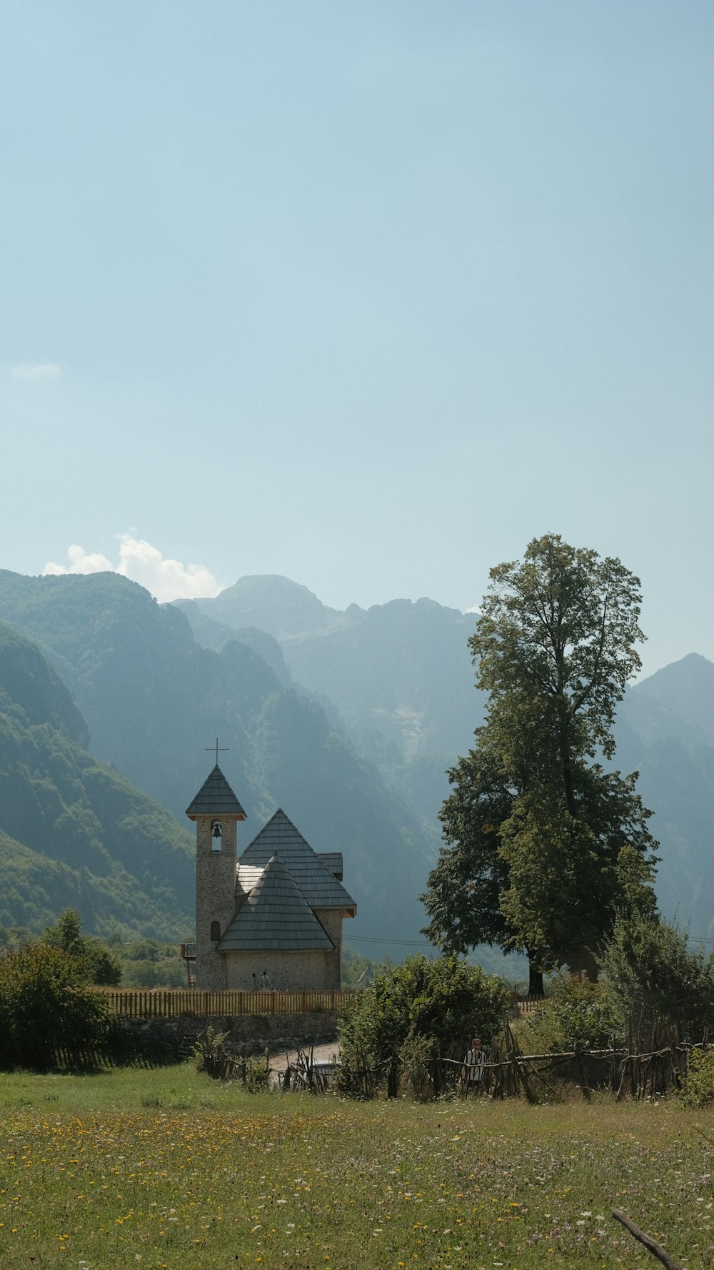 a church in the middle of a field with mountains in the background