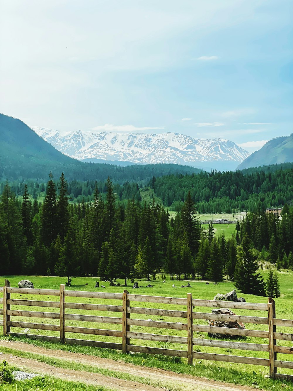 a wooden fence in a field with mountains in the background