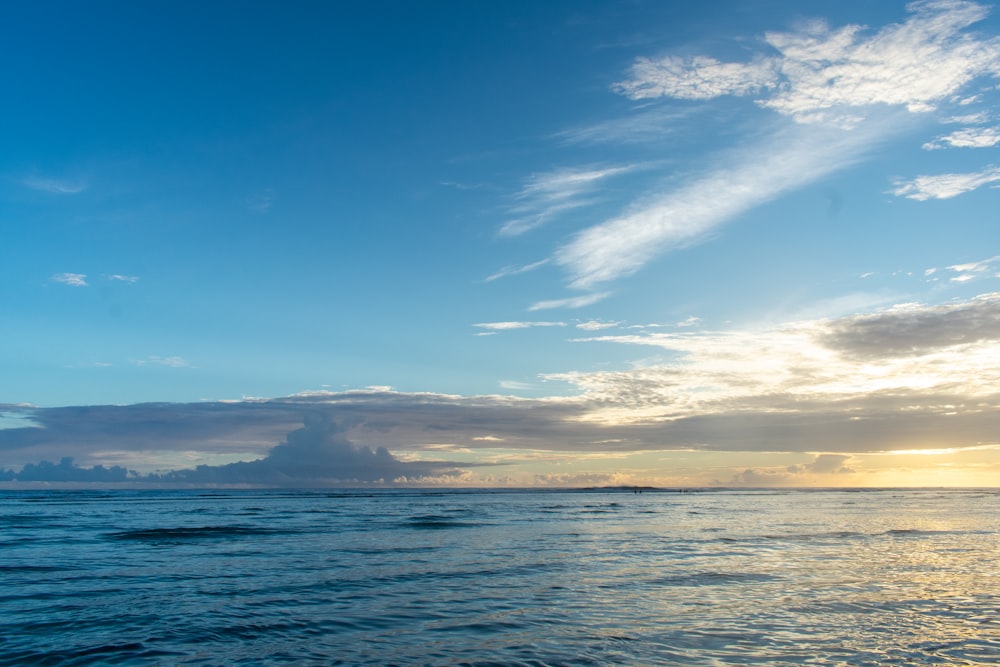 a large body of water under a cloudy blue sky