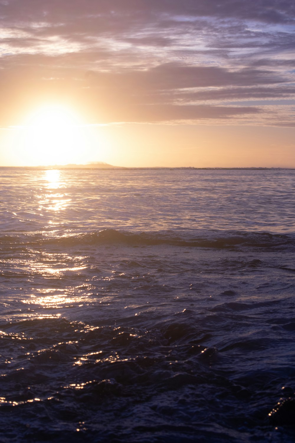 the sun is setting over the ocean on a cloudy day