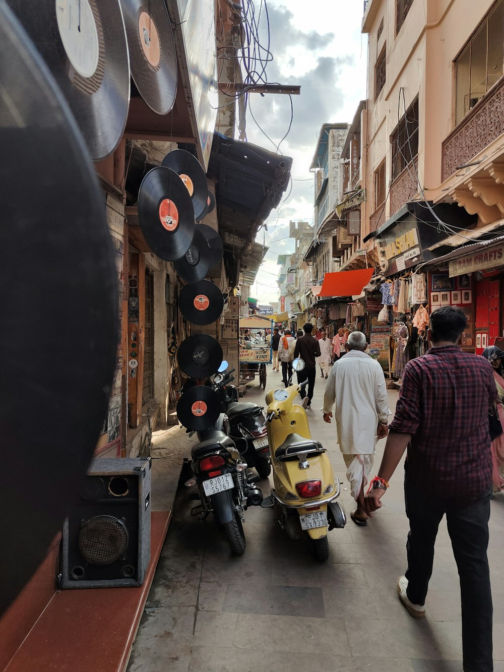 a man walking down a street next to a yellow scooter