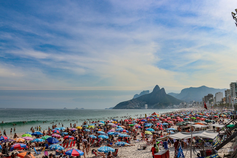 a crowded beach filled with people and umbrellas