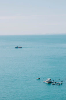 A serene aerial view of a cutting-edge marine research facility perched on stilts above deep blue ocean waters under a clear sky.
