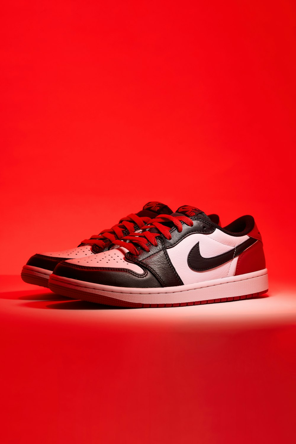 a pair of black and white sneakers on a red background
