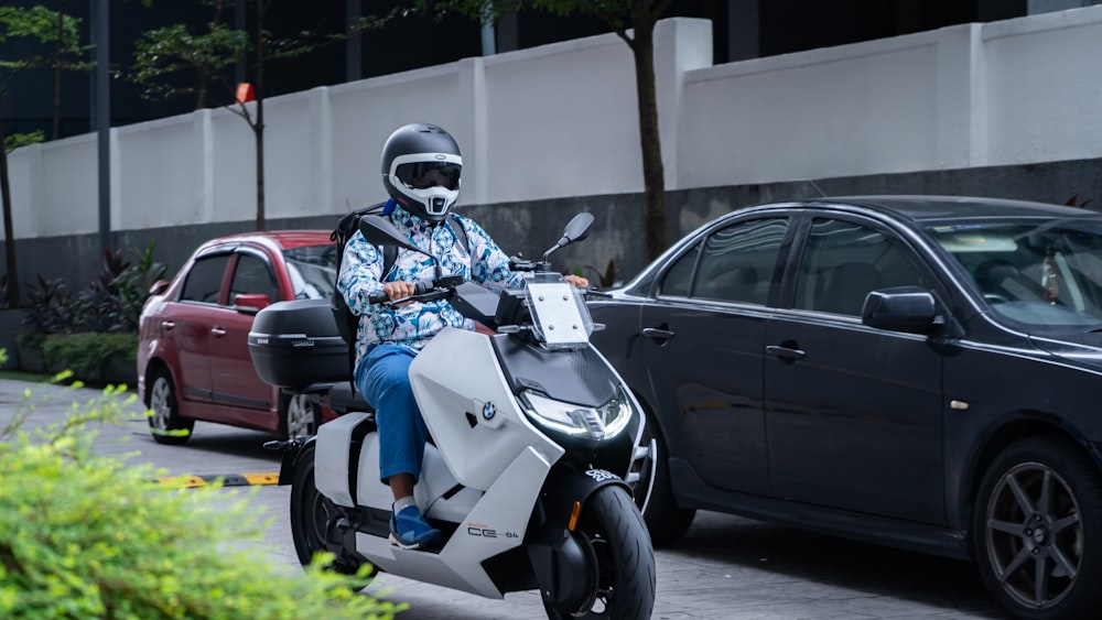 a man riding a scooter down a street next to a car