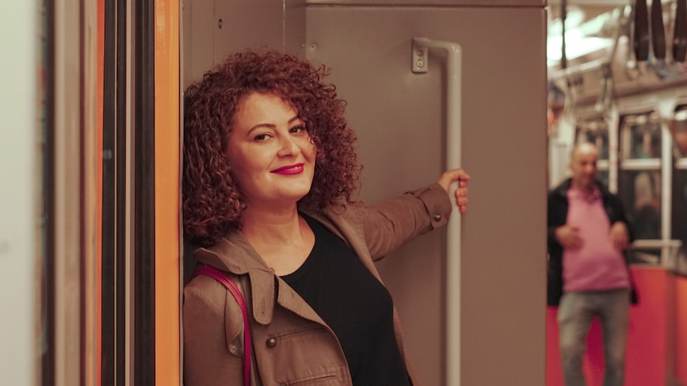 a woman standing on a train with her hand on the door