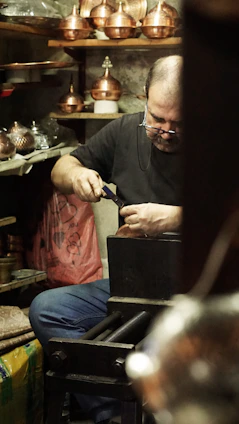 Artisan crafting a copper bracelet with traditional tools under warm lighting
