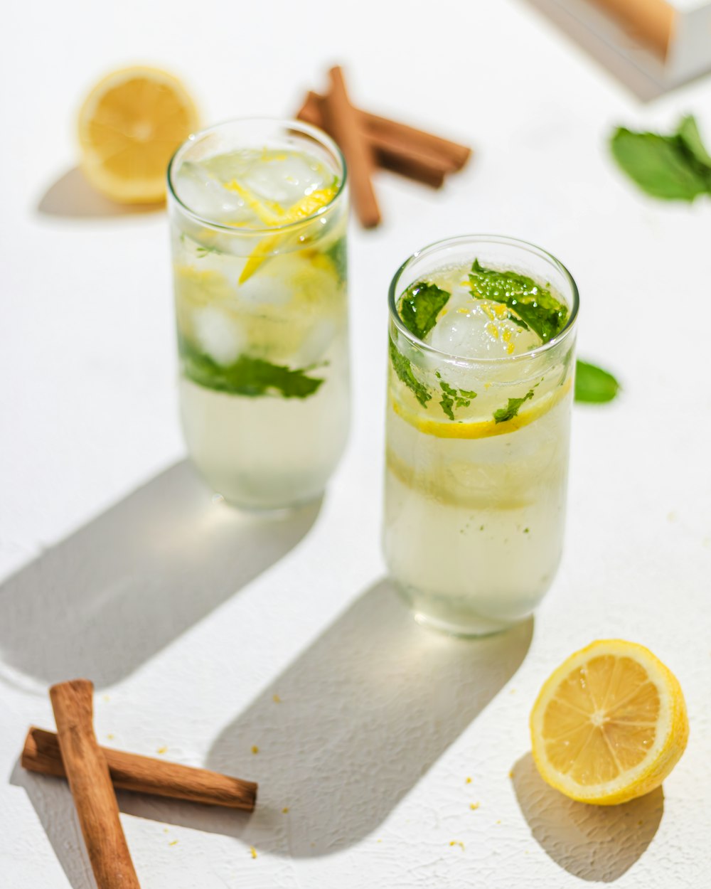 two glasses filled with lemonade and mint on a table