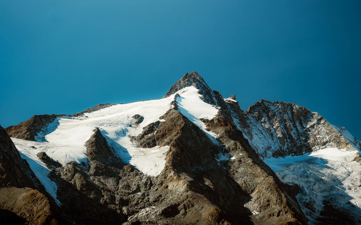 The snow and rock summit of the Grossglockner against a deep blue sky