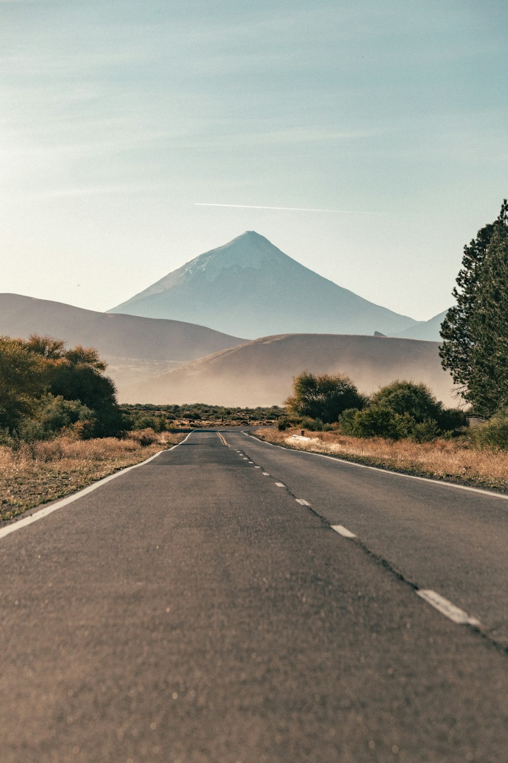 an empty road with a mountain in the background