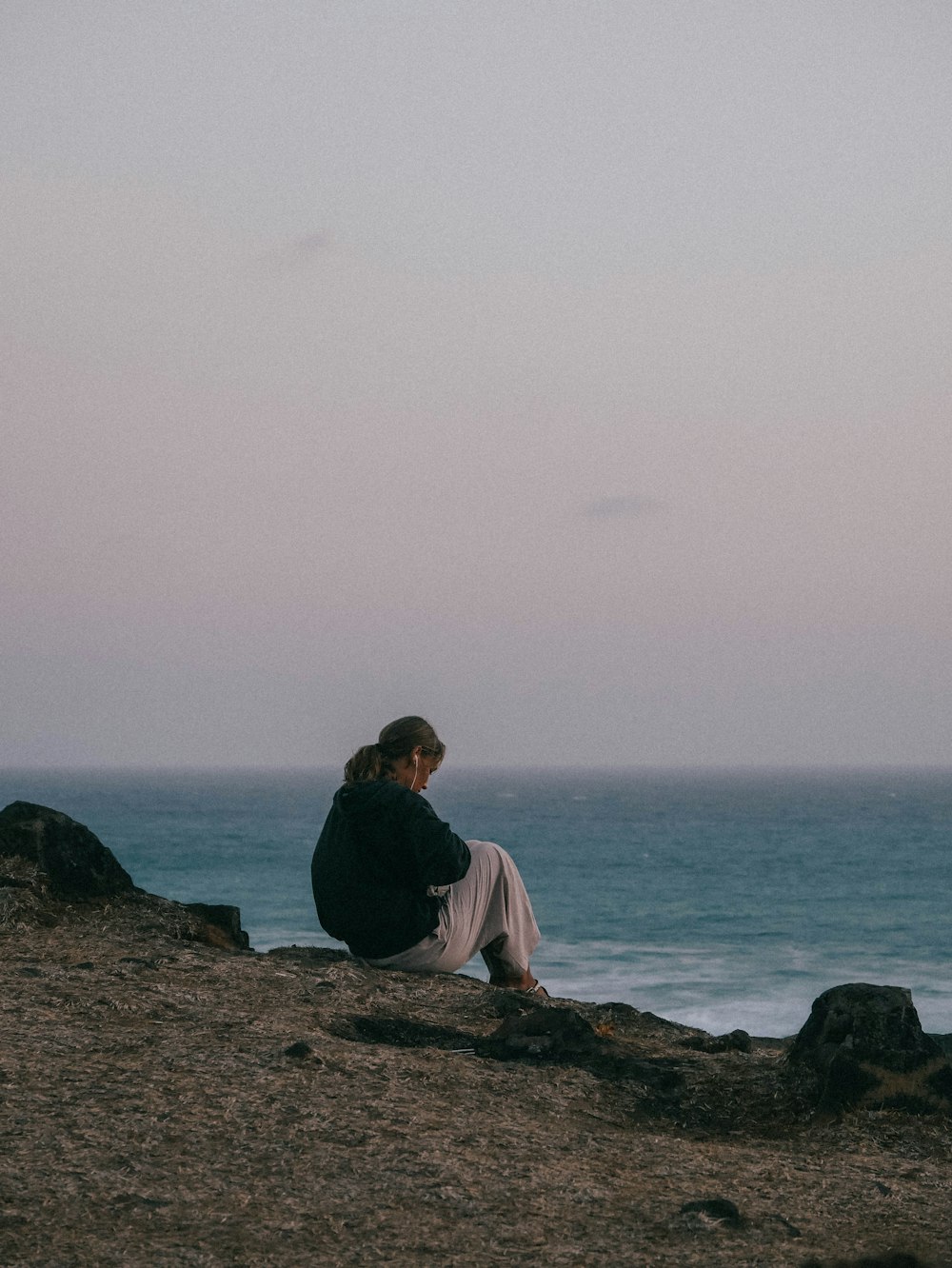 a person sitting on a rock near the ocean