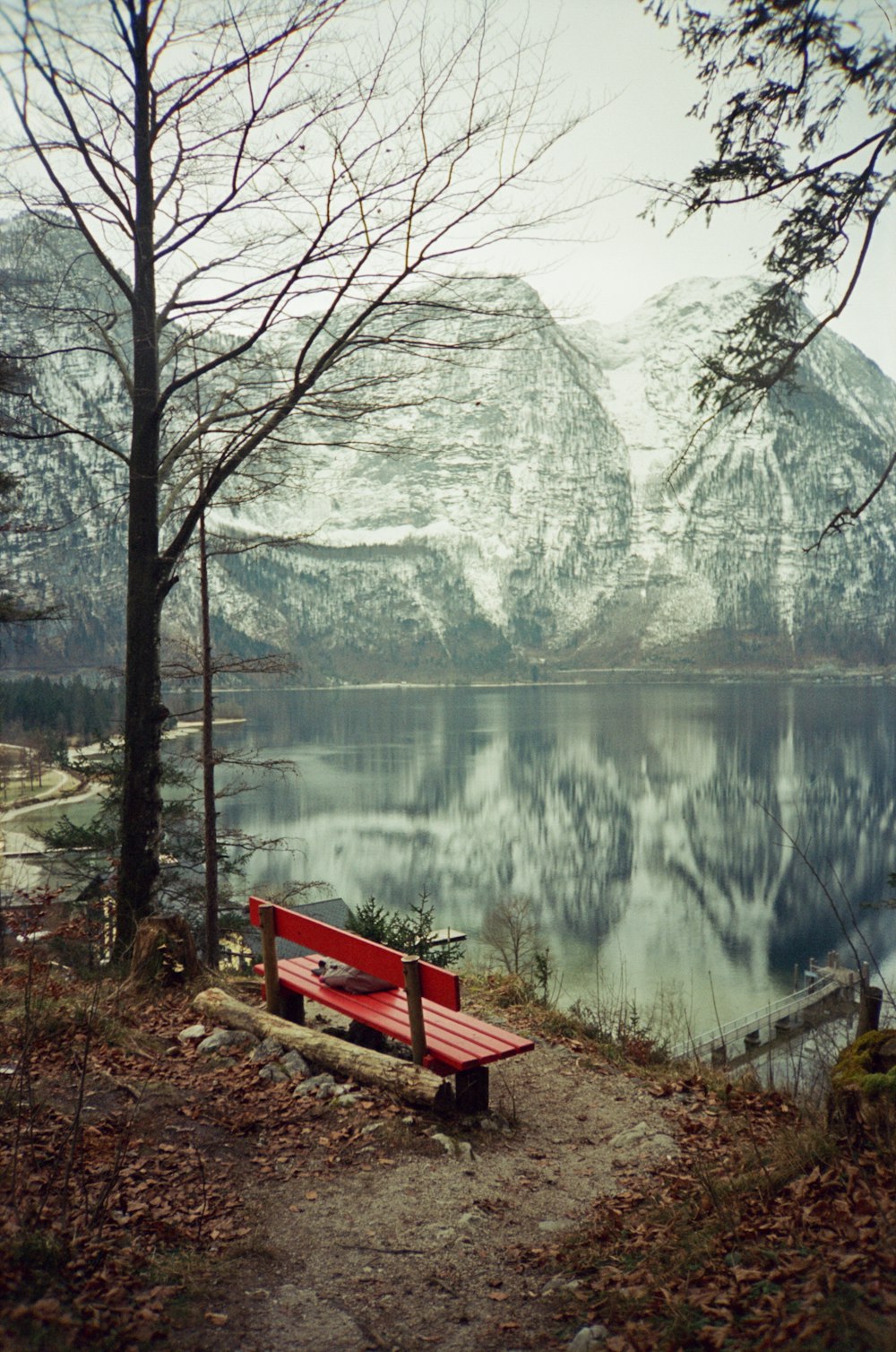 a red bench sitting on the side of a lake