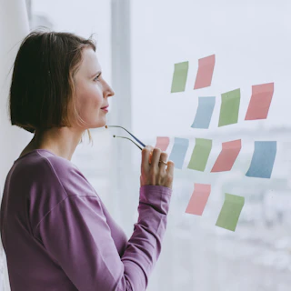 a woman looking out a window with sticky notes on it