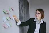 A smiling designer working on a website layout with colorful post-it notes around.
