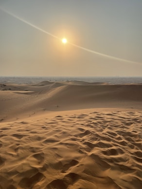 the sun is setting over the sand dunes