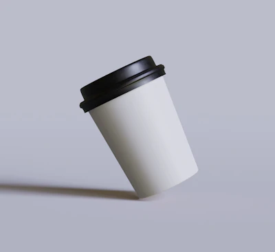 White takeaway cup with a black lid tilted on a lilac surface