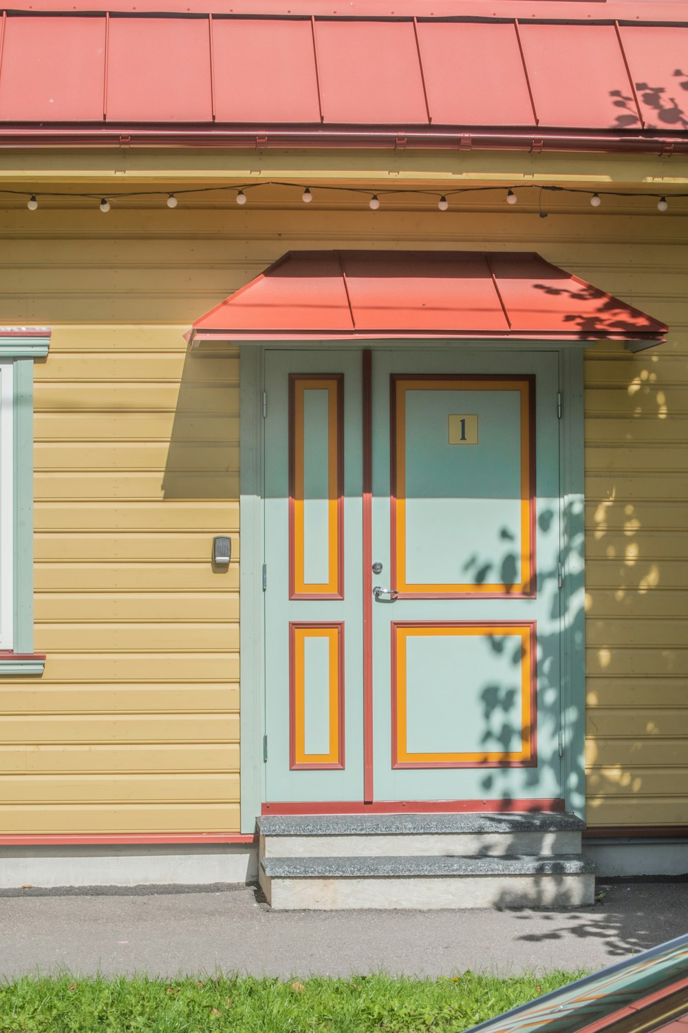 a yellow house with a red roof and a blue door