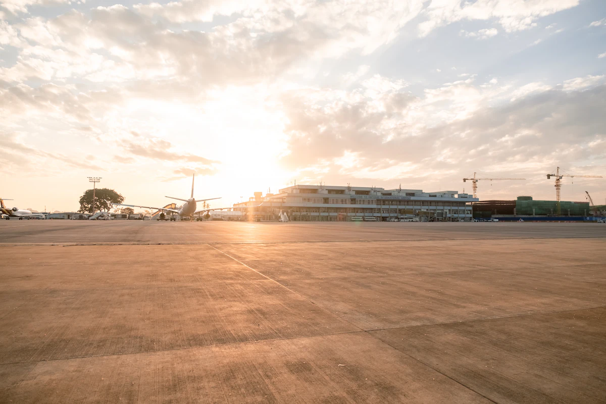 The apron at Entebbe International Airport at sunset, with the terminal and construction cranes behind