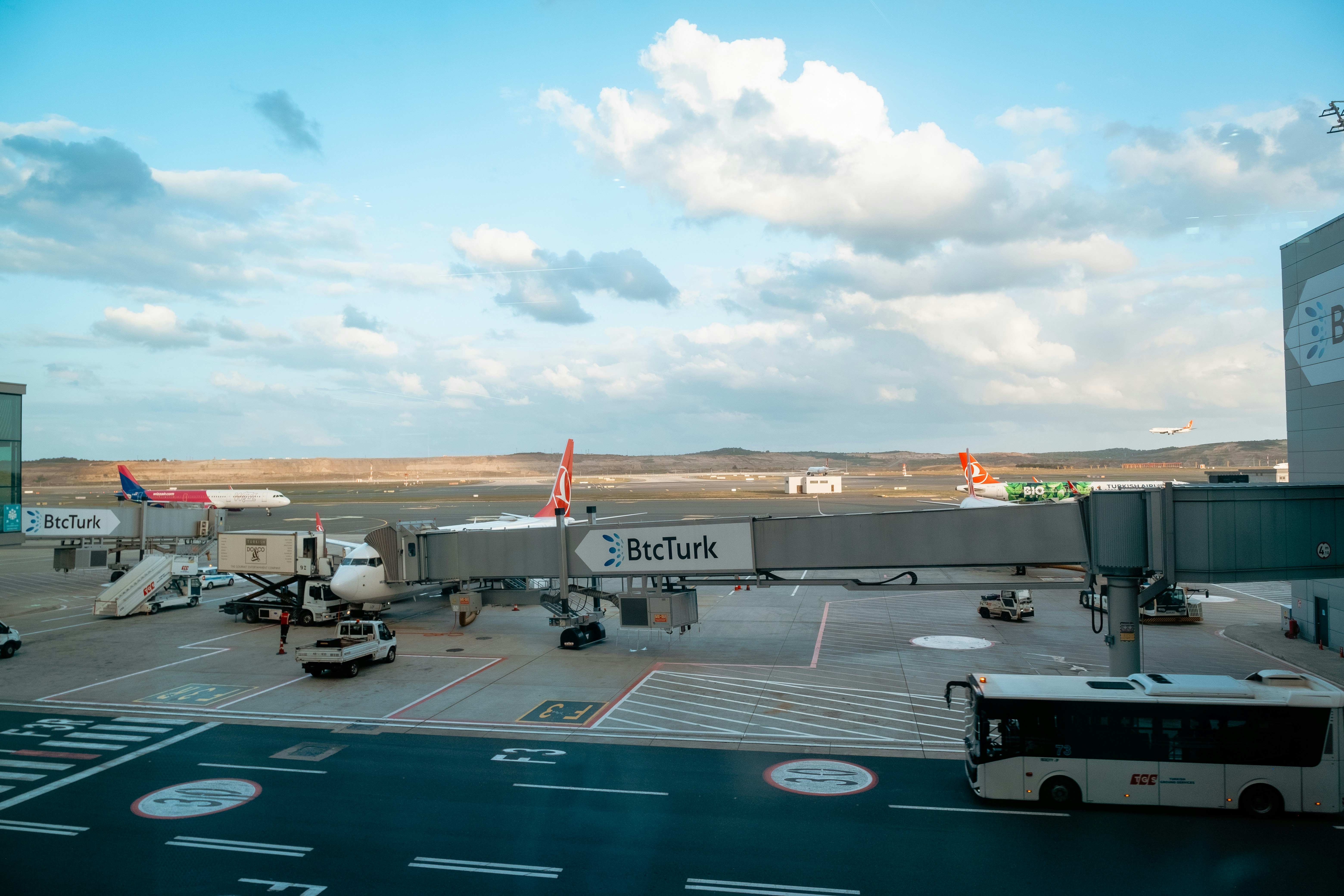 an airport parking lot with a bus parked in front of it, 