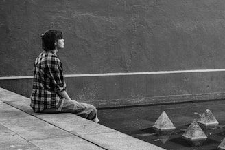 a person sitting on a ledge next to a wall