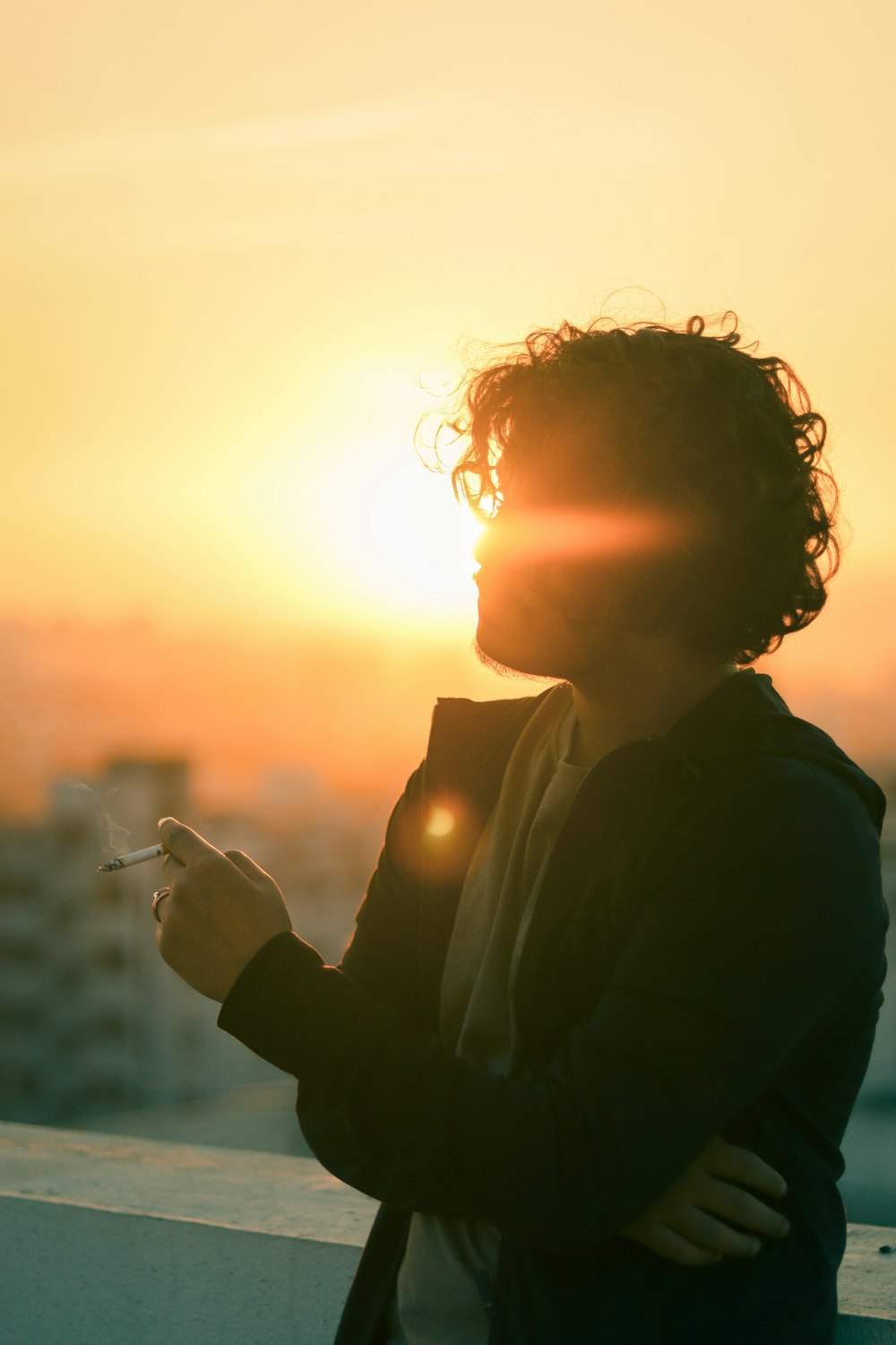 a person standing on a balcony with the sun in the background