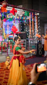 Young girl twirling in a vibrant Bollywood costume with golden accents, capturing festive energy.