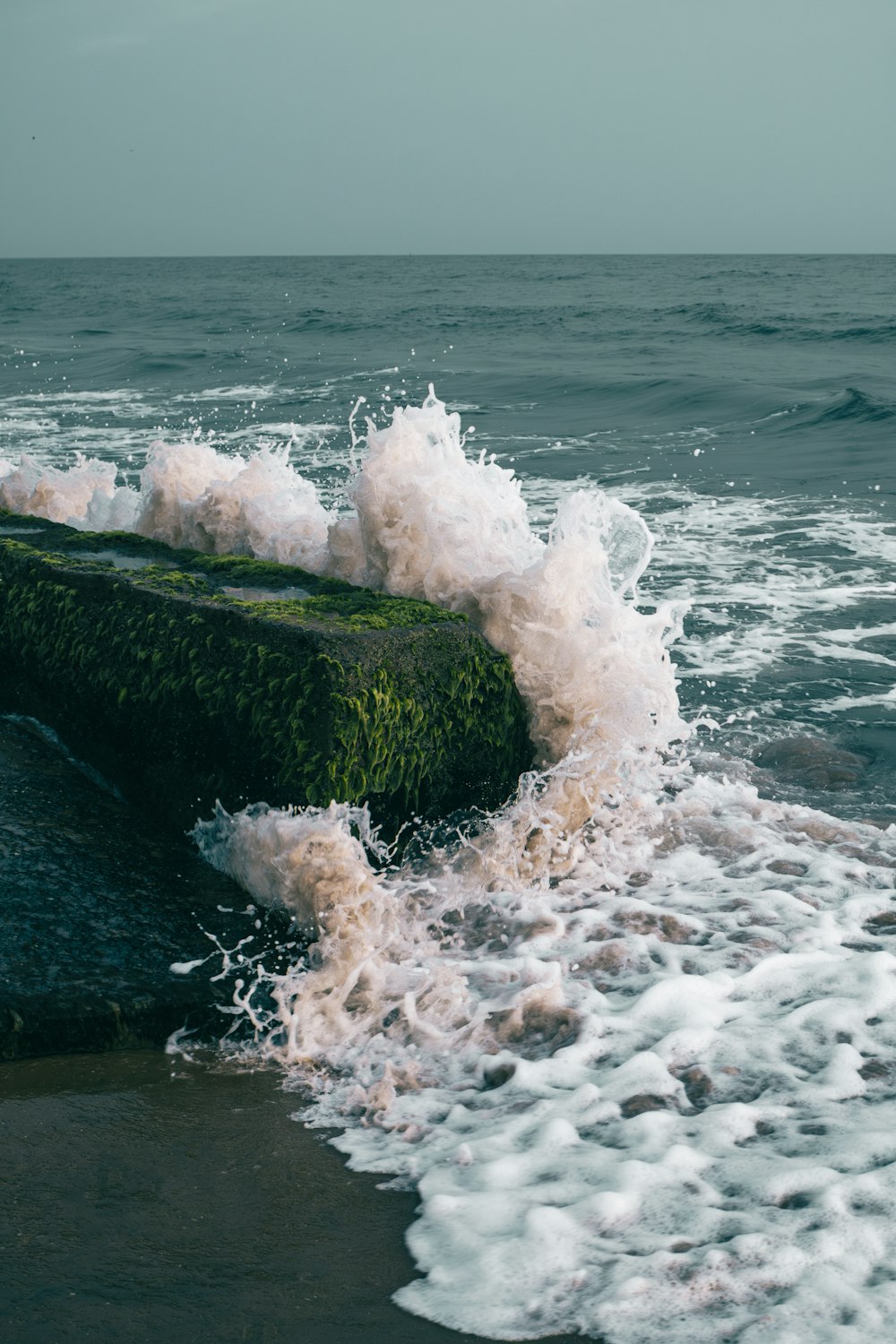 uma onda caindo sobre uma rocha no oceano