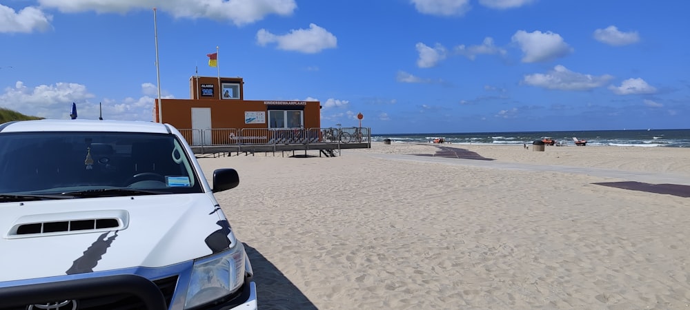 a white truck parked on top of a sandy beach