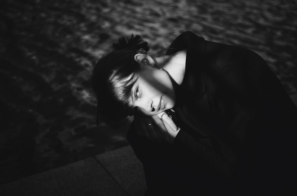 a black and white photo of a woman leaning against a wall