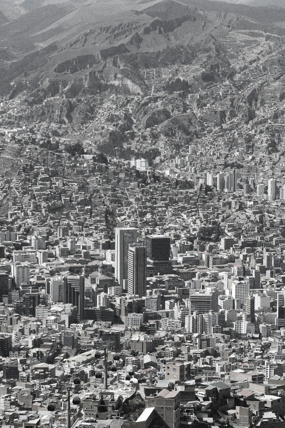 a black and white photo of a city with mountains in the background