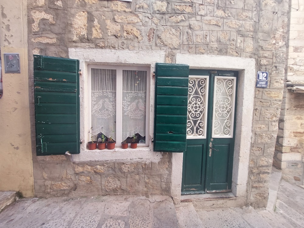 a stone building with green shutters and a window